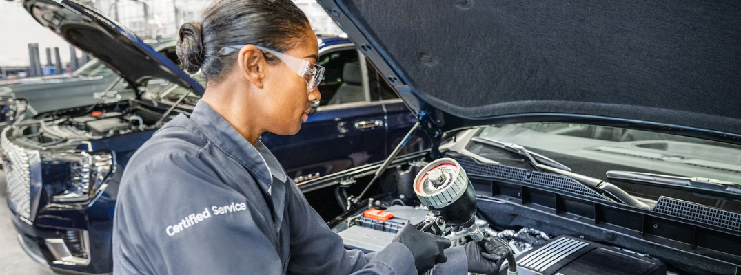 A service technician performing an oil change on a GMC vehicle
